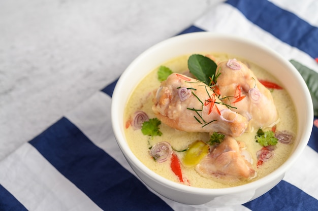 Tom Kha Kai in a bowl with kaffir lime leaves, lemongrass, red onion, galangal and chilli.