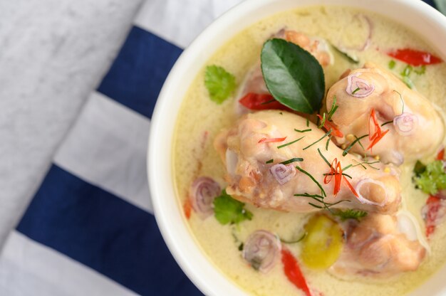 Tom Kha Kai in a bowl with kaffir lime leaves, lemongrass, red onion, galangal and chilli.