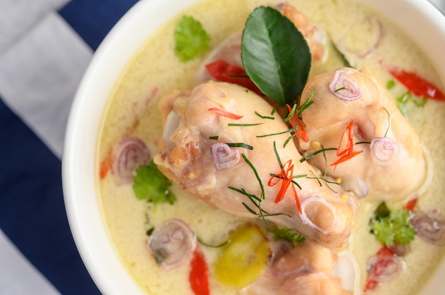 Tom Kha Kai in a bowl with kaffir lime leaves, lemongrass, red onion, galangal and chilli.