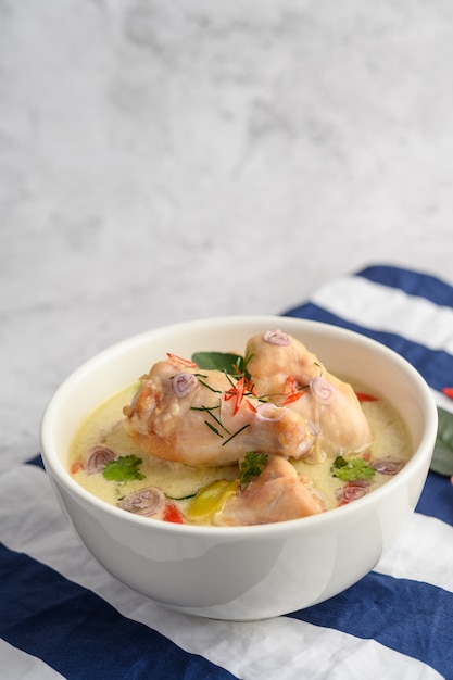 Tom Kha Kai in a bowl with kaffir lime leaves, lemongrass, red onion, galangal and chilli.