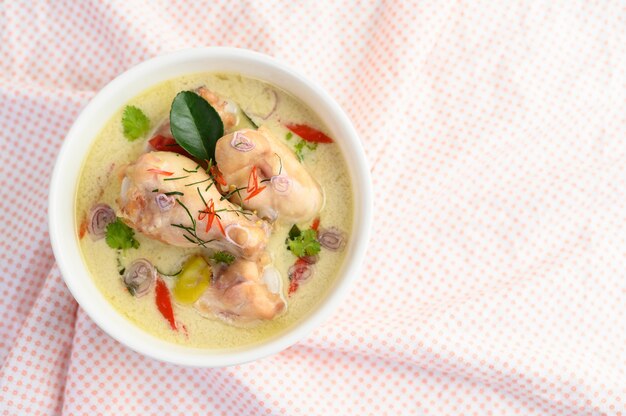 Tom Kha Kai in a bowl with kaffir lime leaves, lemongrass, red onion, galangal and chilli.