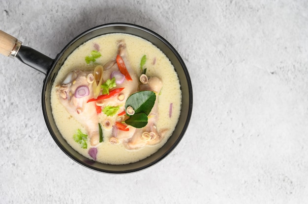 Tom Kha Kai in a pan frying with kaffir lime leaves, lemongrass, red onion, galangal and chilli.