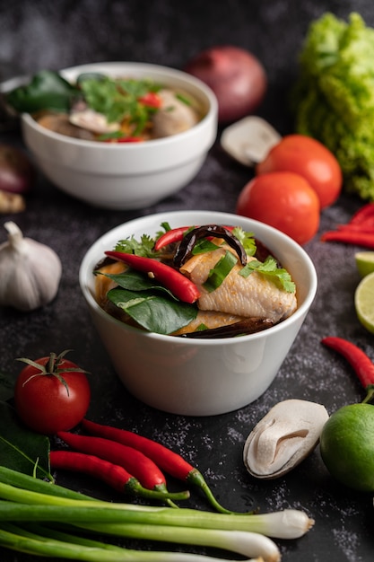 Tom yum chicken with chili, coriander, dried chili, kaffir lime leaves, mushroom and lemongrass in a bowl