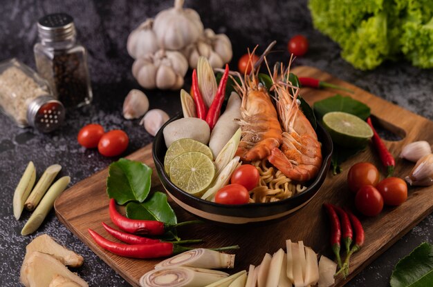 Tom Yum Kung in a bowl with tomato, chili, lemongrass, garlic, lemon, and kaffir lime leaves