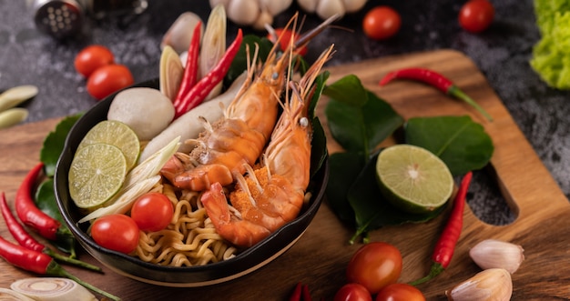 Tom Yum Kung in a bowl with tomato, chili, lemongrass, garlic, lemon, and kaffir lime leaves