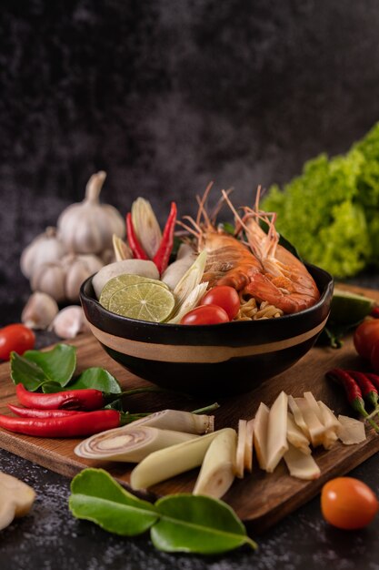 Tom Yum Kung in a bowl with tomato, chili, lemongrass, garlic, lemon, and kaffir lime leaves