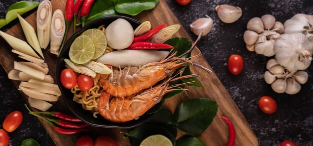 Tom Yum Kung in a bowl with tomato, chili, lemongrass, garlic, lemon, and kaffir lime leaves