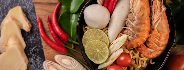 Tom Yum Kung in a bowl with tomato, chili, lemongrass, garlic, lemon, and kaffir lime leaves