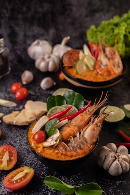 Tom Yum Kung in a bowl with tomato, chili, lemongrass, garlic, lemon, and kaffir lime leaves