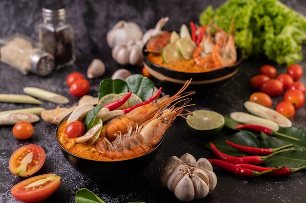 Tom Yum Kung in a bowl with tomato, chili, lemongrass, garlic, lemon, and kaffir lime leaves