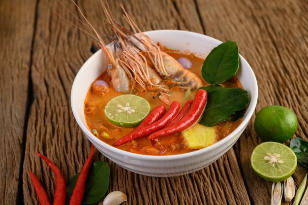 Tom Yum Kung Thai hot spicy soup shrimp with lemon grass,lemon,galangal and chilli on wooden table, Thailand Food