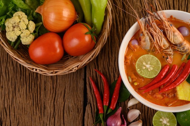 Tom Yum Kung Thai hot spicy soup shrimp with lemon grass,lemon,galangal and chilli on wooden table, Thailand Food