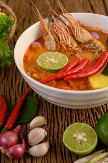 Free photo tom yum kung thai hot spicy soup shrimp with lemon grass,lemon,galangal and chilli on wooden table, thailand food
