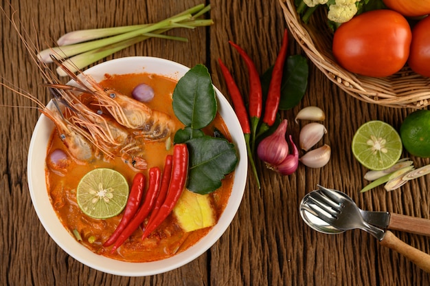 Tom Yum Kung Thai hot spicy soup shrimp with lemon grass,lemon,galangal and chilli on wooden table, Thailand Food