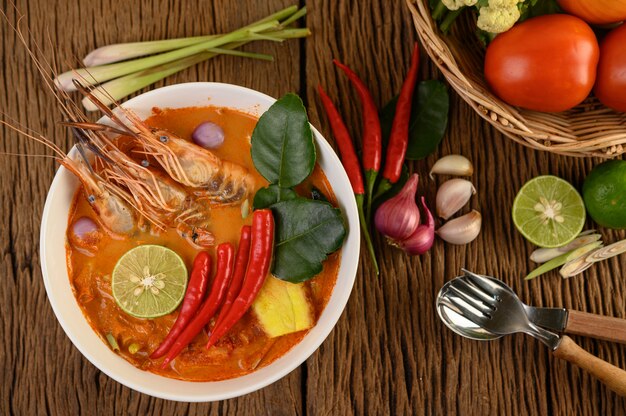 Tom Yum Kung Thai hot spicy soup shrimp with lemon grass,lemon,galangal and chilli on wooden table, Thailand Food