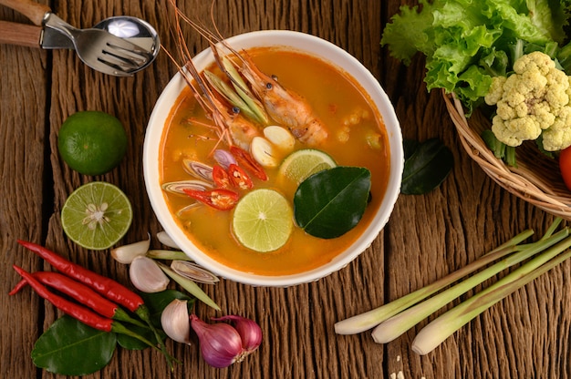 トムヤムクンタイホットスパイシーなスープエビとレモングラス、レモン、ガランガル、唐辛子、木製のテーブル、タイ料理