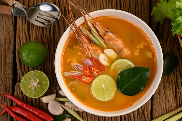 Tom Yum Kung Thai hot spicy soup shrimp with lemon grass,lemon,galangal and chilli on wooden table, Thailand Food