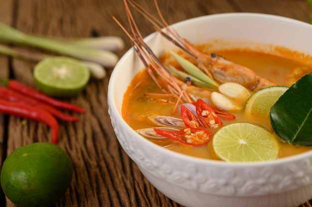 Tom Yum Kung Thai hot spicy soup shrimp with lemon grass,lemon,galangal and chilli on wooden table, Thailand Food