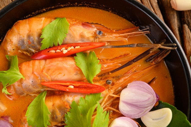 Tom Yum Kung Thai hot spicy soup shrimp with lemon grass,lemon,galangal and chilli on wooden table, Thailand Food