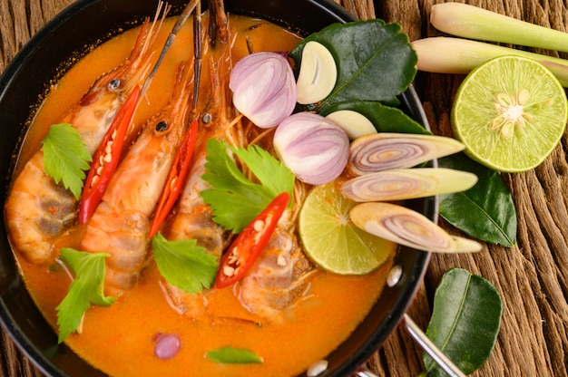 Tom Yum Kung Thai hot spicy soup shrimp with lemon grass,lemon,galangal and chilli on wooden table, Thailand Food