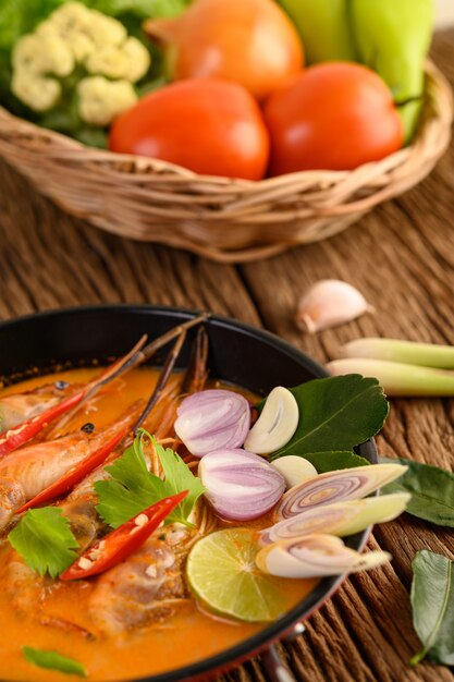 Tom Yum Kung Thai hot spicy soup shrimp with lemon grass,lemon,galangal and chilli on wooden table, Thailand Food