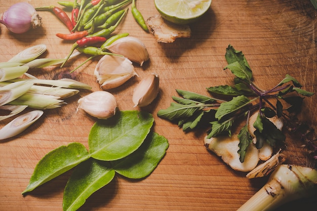 Tom Yum spices that are placed on a brown wood cutting board and have a dark brown wood .