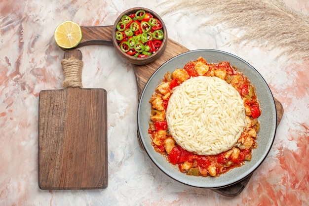 Tomato chicken meal with white rice pepper salad and small cutting board
