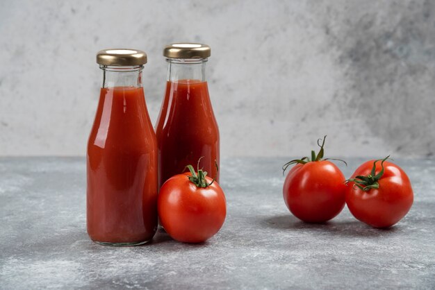 Tomato juice in glass jars on a marble background.
