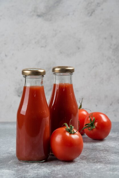 Tomato juice in glass jars on a marble background.