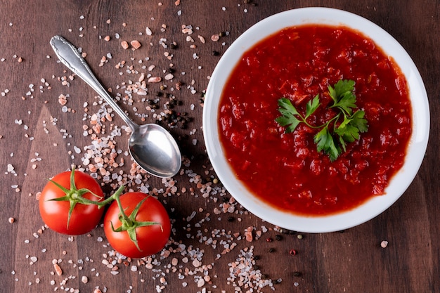 Tomato pasta soup with salt top view on wooden surface