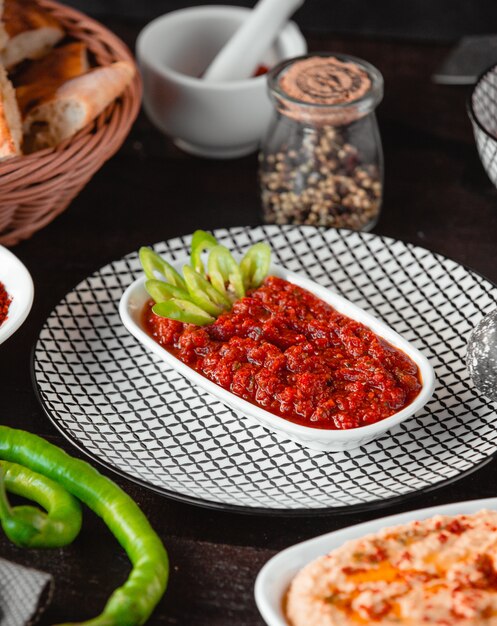 Tomato sauce inside white plate with lettuce.