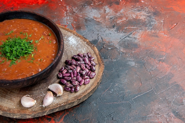Бесплатное фото Томатный суп фасоль и чеснок на деревянной разделочной доске на столе смешивания цветов