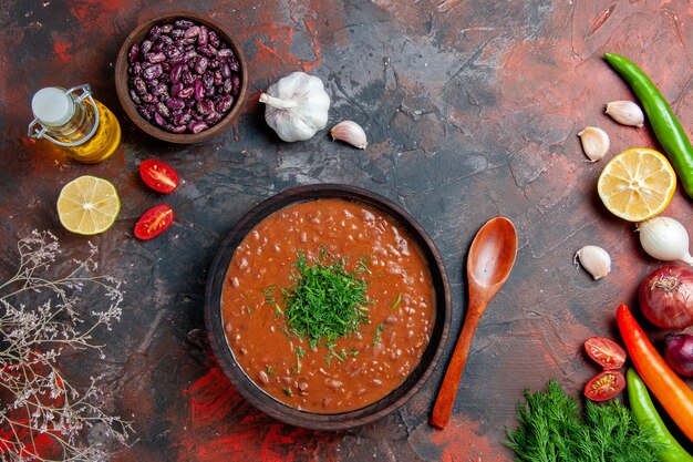 Tomato soup oil bottle beans lemon and a bunch of green on mixed color table