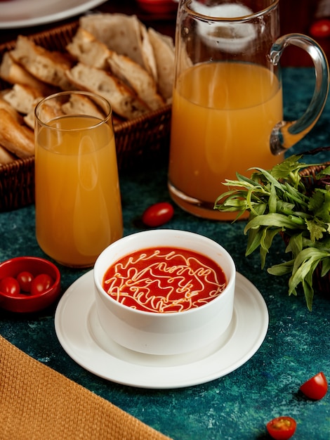 白いボウルとジュースのガラスのトマトスープ