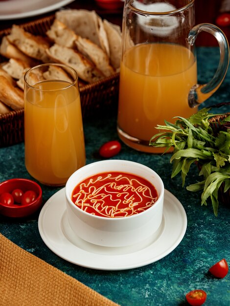 Tomato soup in a white bowl and a glass of juice