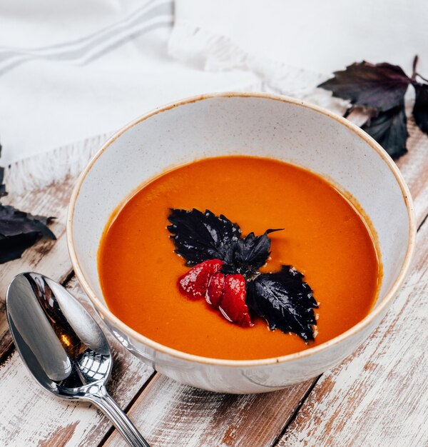 Tomato soup with basil on the table