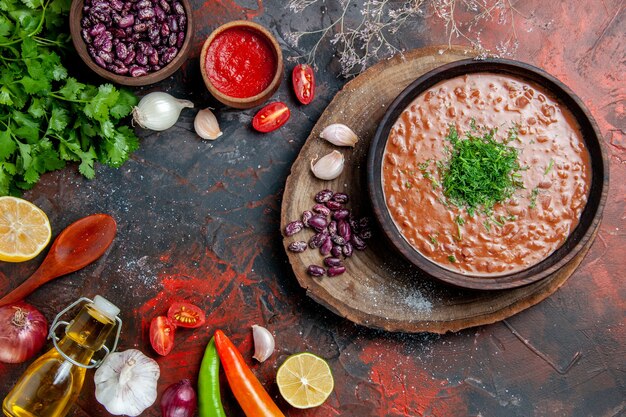 Tomato soup with a bunch of green oil bottle garlic and spoon on mixed color table