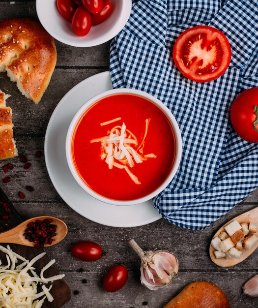 Tomato soup with grated cheese top view on the table