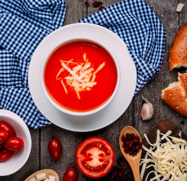 Free photo tomato soup with grated cheese top view on the table