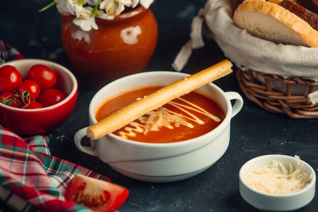 tomato soup with grated parmesan on top and crispy breadstick