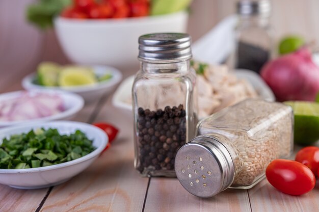 Tomatoes, along with a jar of sesame seeds, placed on a wooden table