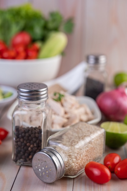 Tomatoes, along with a jar of sesame seeds, placed on a wooden table