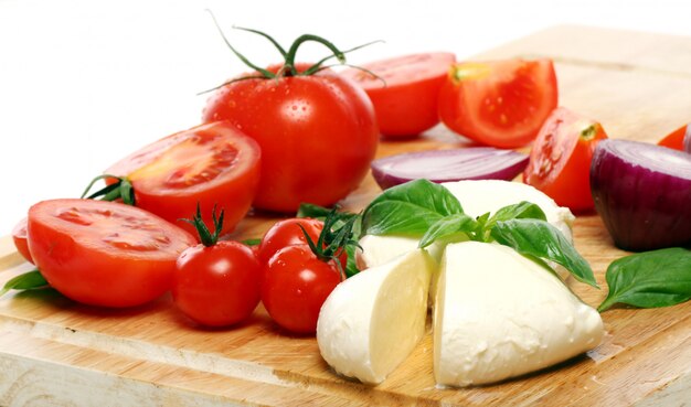 Tomatoes, basil and mozzarella on wooden board