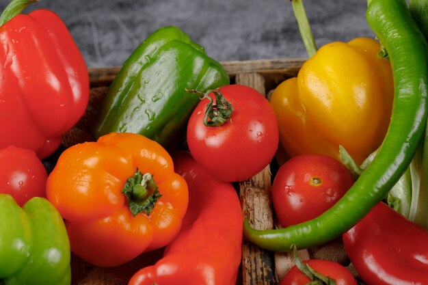 Tomatoes, bell peppers and green chilies in a rustic tray. Top view.