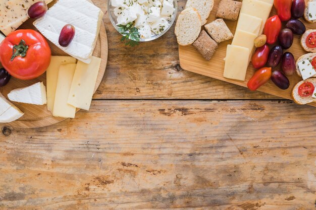 Tomatoes; cheese blocks and grapes on wooden desk