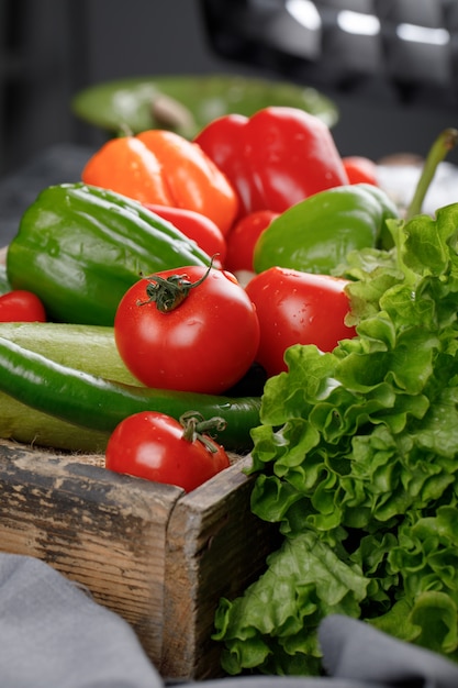 Tomatoes, cucumbers, greenery in a wooden tray.