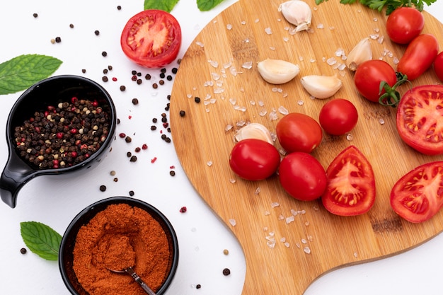 Free photo tomatoes on cutting board with spices top view concept on white surface