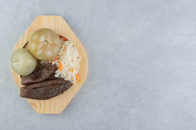 Tomatoes, eggplants and sauerkraut on a wooden plate   