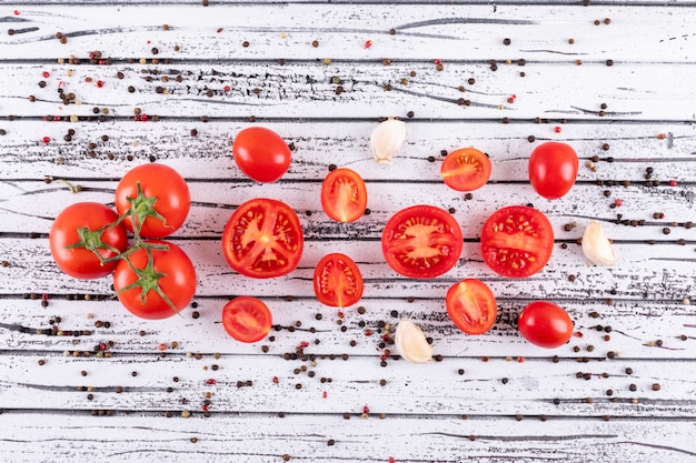 Foto gratuita vista superiore dell'aglio e del pepe nero di pomodori su struttura di legno bianca