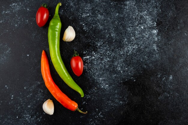 Tomatoes, garlic and chilli peppers on marble surface.